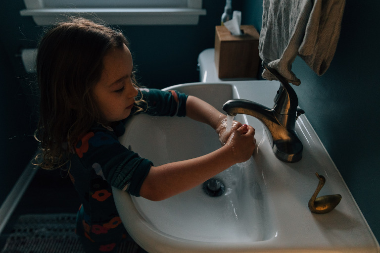 Girl washes hands in a sink. 