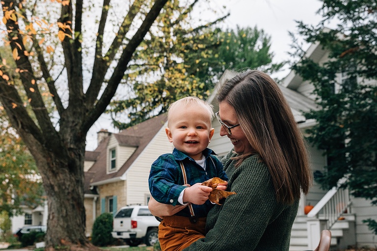 Mothers hold toddler boy holding fall leaves