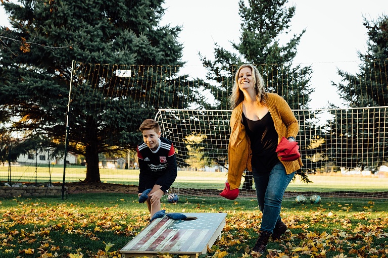 Mother and son toss bean bags in the backyard on a fall evening.