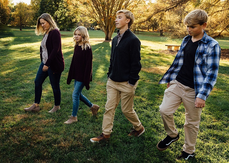Mother walks with her three children in an open field at sunset. 
