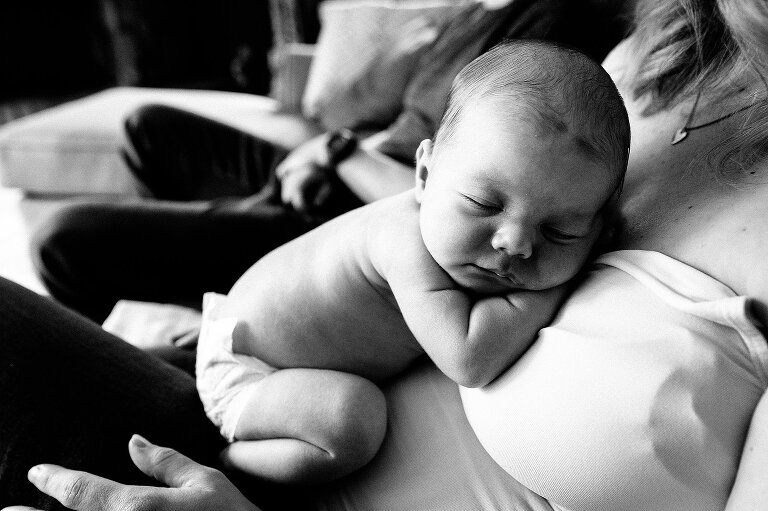 Newborn sleeps on his mother's chest. Black and white. At-home newborn photography session