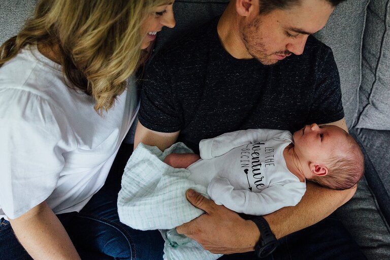 Mother and father look at their newborn son for an at-home photography session