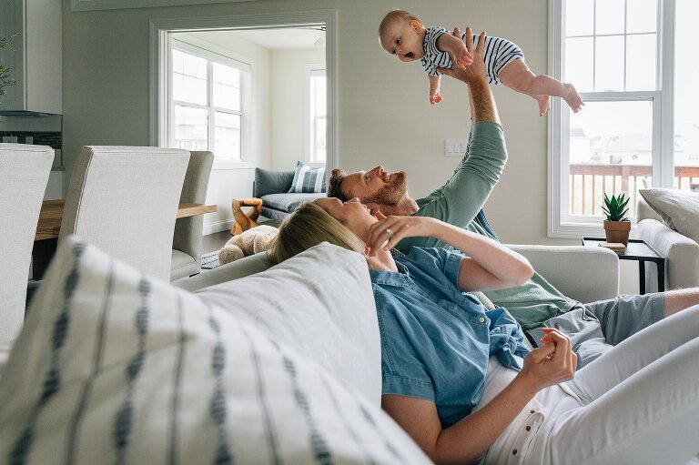 Dad holds up baby while baby looks at mom 