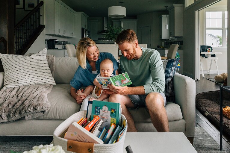Family of three reads book together on the couch during Family Photography in MIddleton