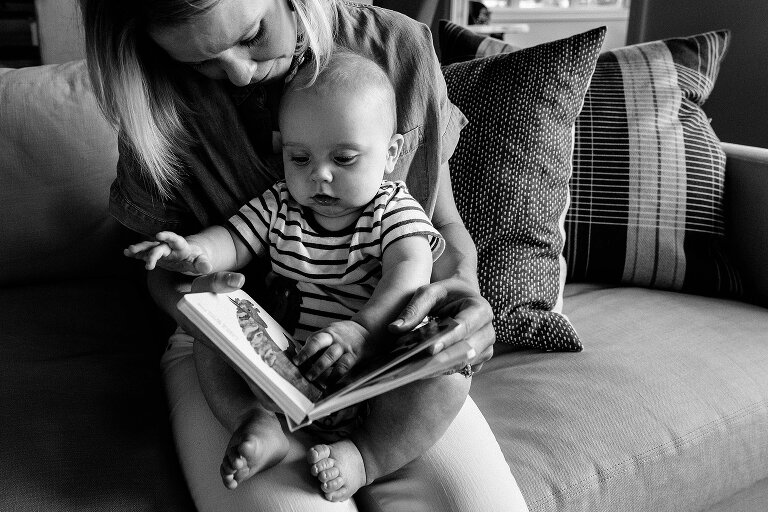 mom holds baby and reads book. black and white