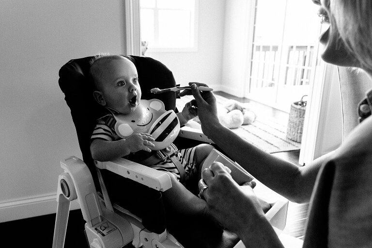 Baby opens mouth for spoonful of mashed bananas