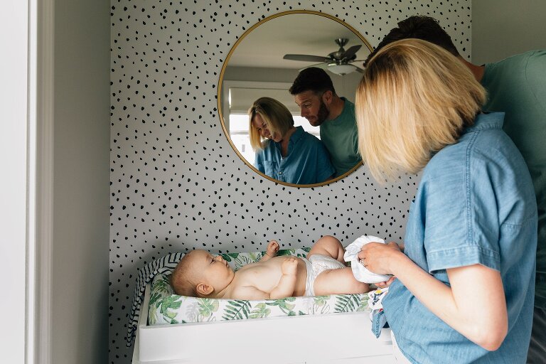 mom and dad smile at infant on changing table