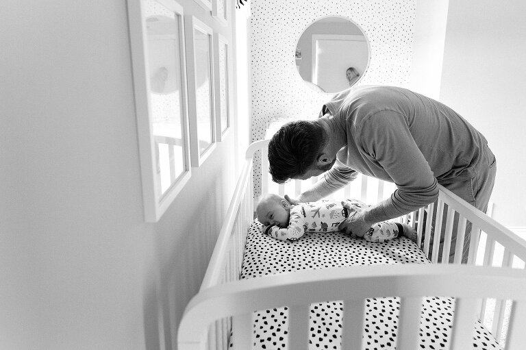 dad wakes up infant from nap in a crib. Family Photography in MIddleton