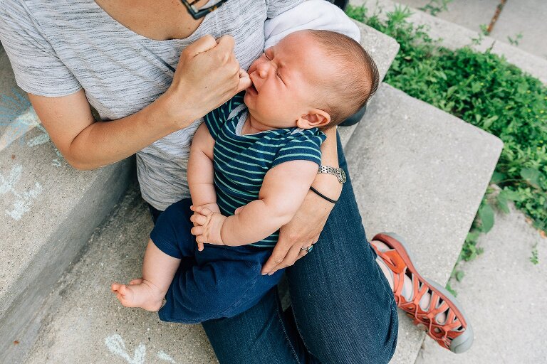 Mom offers a finger for infant to suck on while crying.