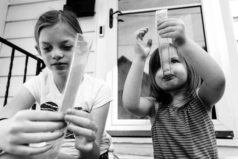 Girls eat Freezer Pops on a the front stoop.