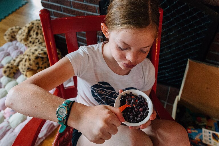 Pre-teen girl eats blueberries on an ordinary summer Saturday morning