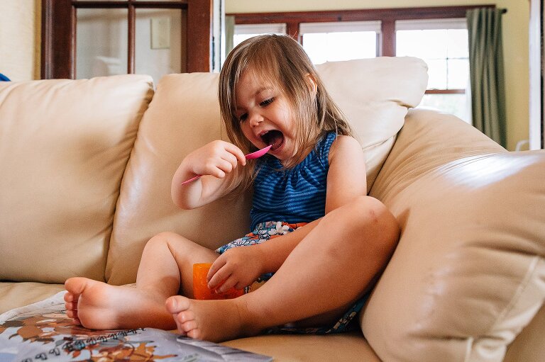 Young girl eats frozen blueberries from the couch