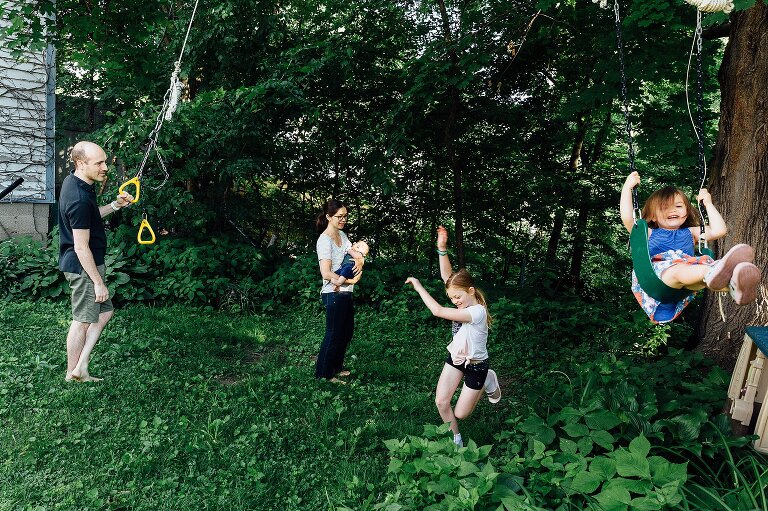 Family of five scene from the backyard. Everyone is smiling and interacting on an ordinary summer Saturday morning