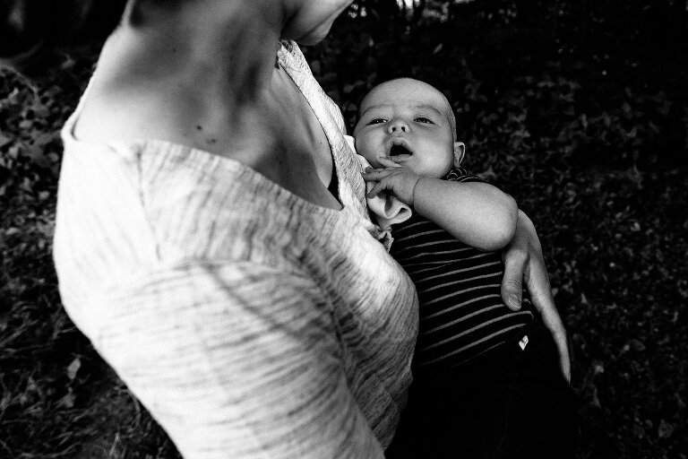 Black and white. Mom holds infant boy while he looks up at her. 