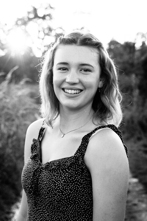black and white. teen girl smiling and making eye contact with camera. 