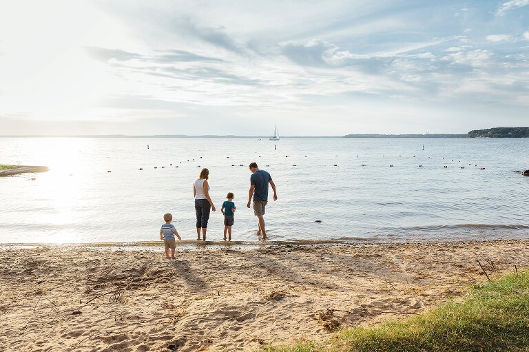 Family of four at the beach near sunset. Sailboat on the horizon. 