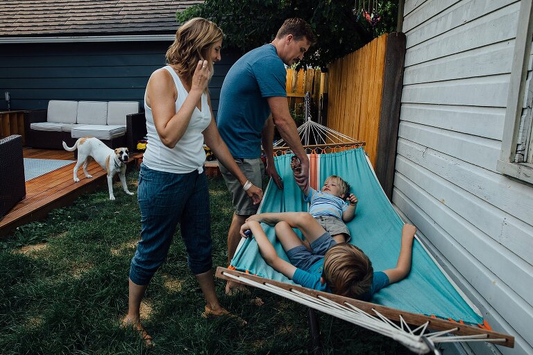 Family of four and a dog play on a backyard hammock. great for Backyard Family Photos. 