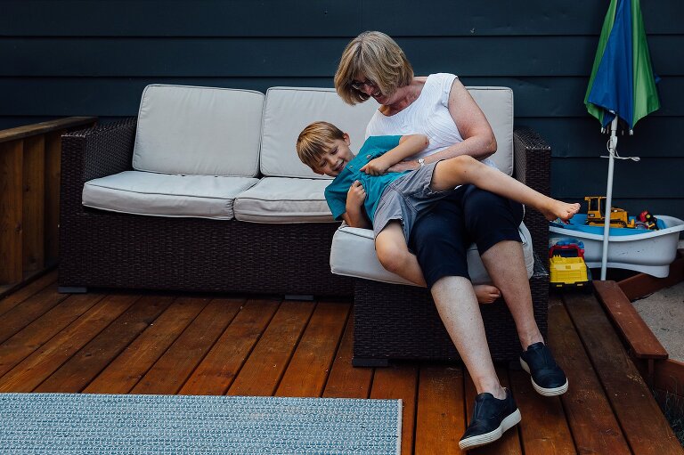 Grandma playfully leans with grandson as they sing a song. backyard family photos