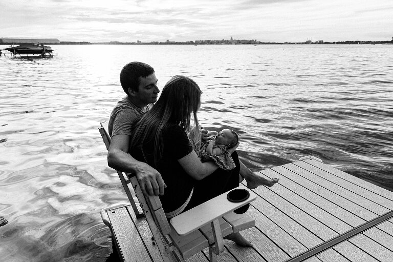 Two parents sit on a bench on the lake in their backyard with Capitol in background 