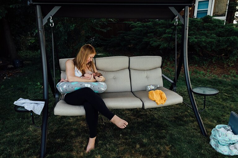 Mom nurses newborn on a swing in her backyard