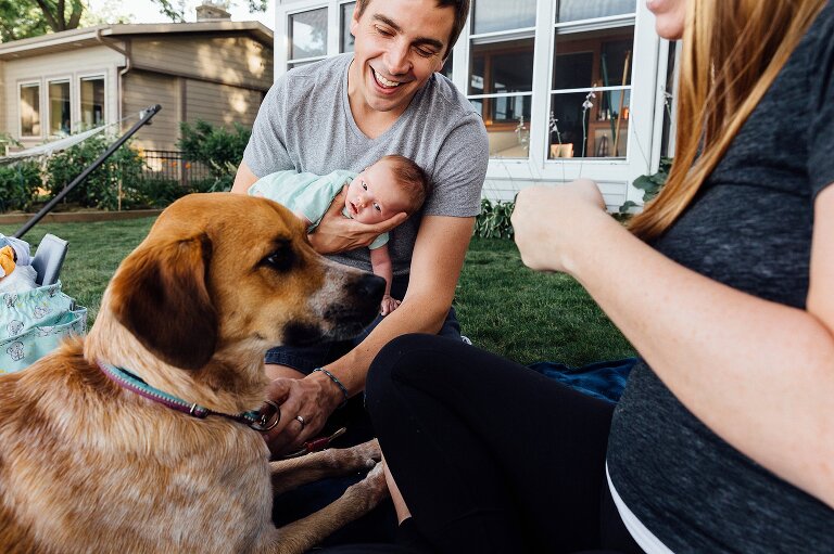 Dad waits for a treat while newborn is in a football hold by dad and looks on
