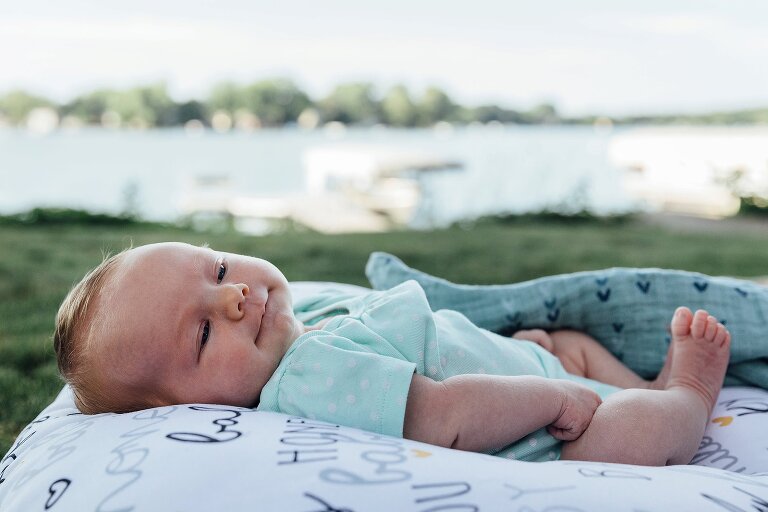 Newborn lounges in backyard on the lake