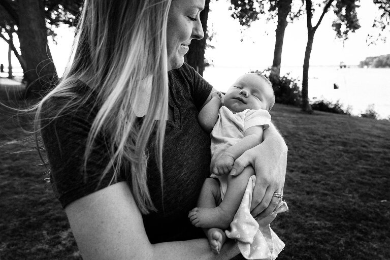 black and white. Mom holds newborn and smiles