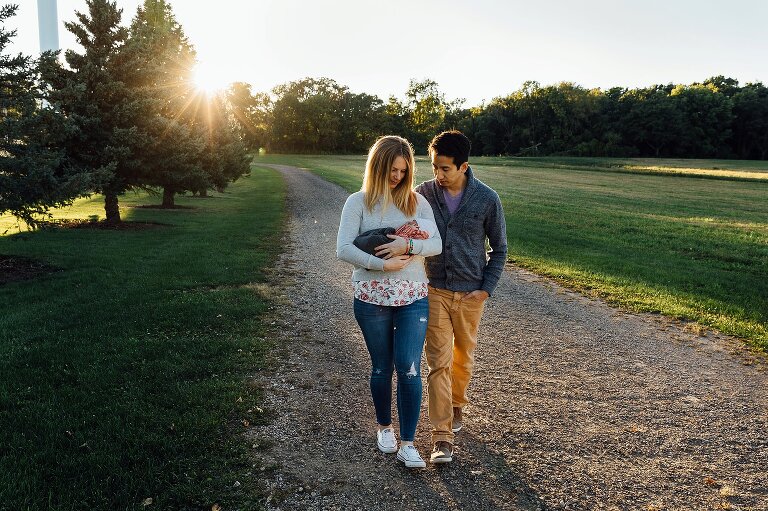 New parents take a walk with their newborn down a sunny path