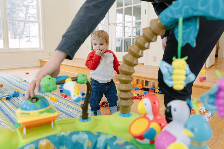 Dad pushes a button on a toddler toy while son watches 