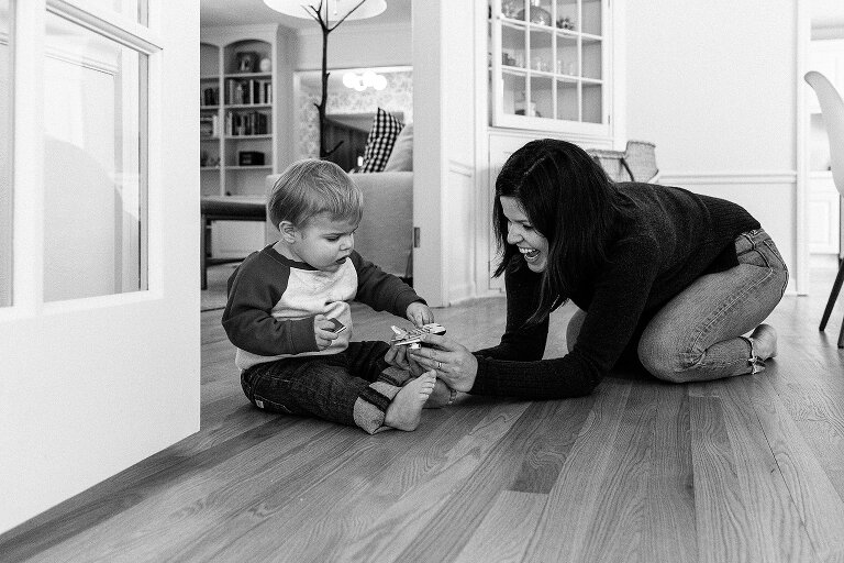 Mom shows toddler son a toy airplane.
