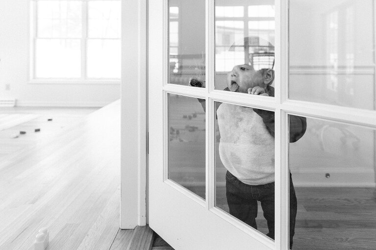 Toddler licks an interior door window.