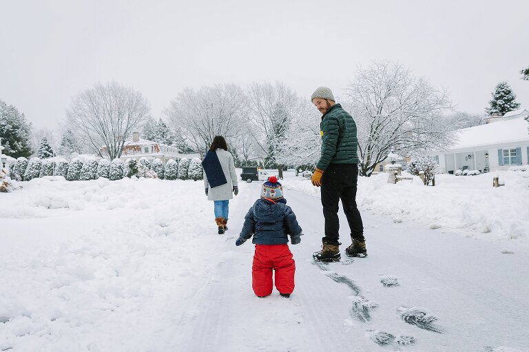 A family of three watch a snowplow on a snowy day
