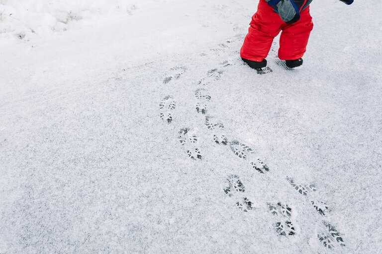 Toddler makes boot footprints in the snow