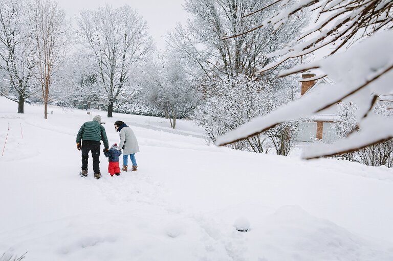 Mom, Dad, and toddler walk down a snowy path