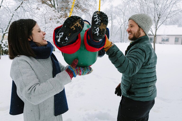 Mom and Dad push toddler on a swing on a snowy day