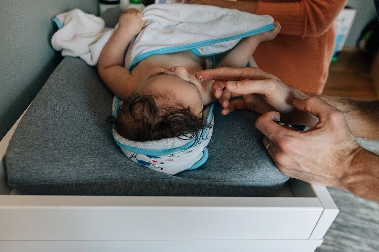 Father applies ointment to infants face.