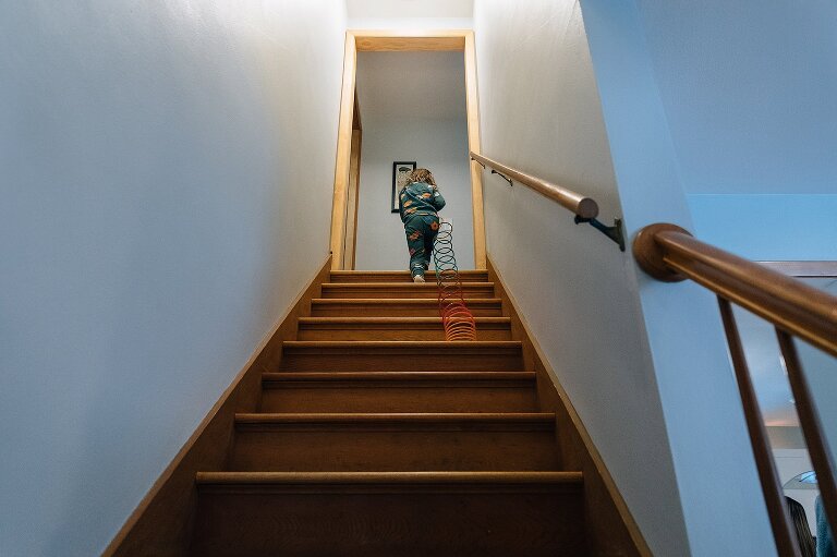 girl pulls a Slinky up the stairs