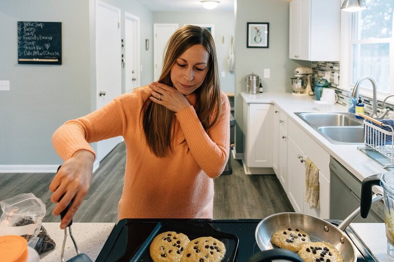 mom holds back hair while flipping chocolate chip winter sunday pancakes in the kitchen 