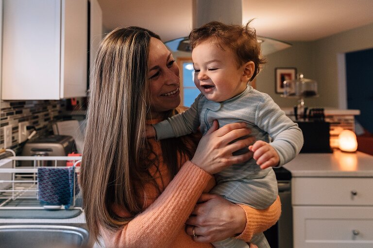 Mom holds infant in the kitchen, infant smiles