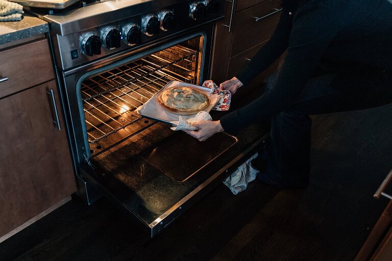 Person pulls finished apple pie out of oven