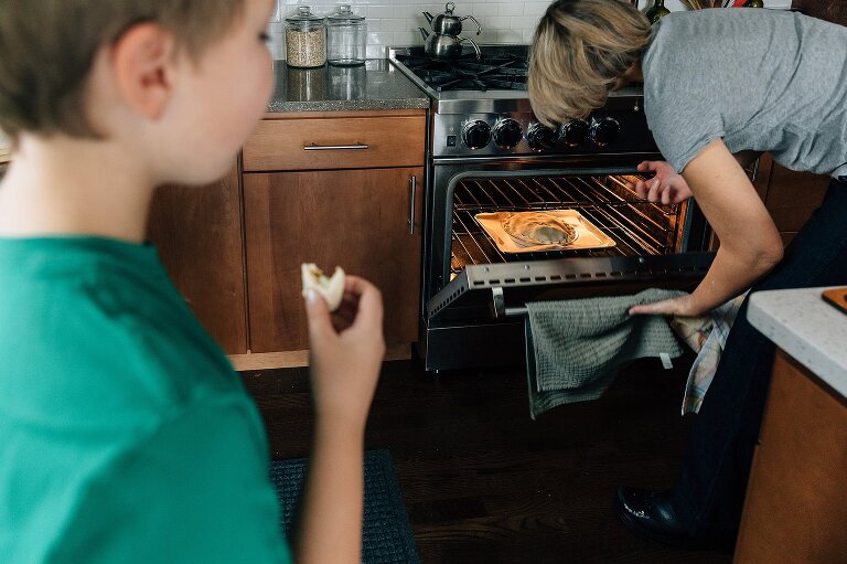 Pie goes in oven while boy stands at edge of frame eating an apple