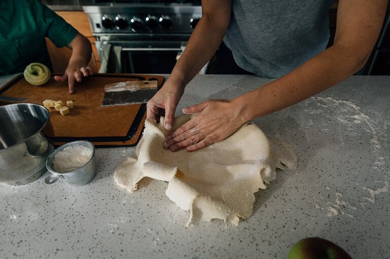 Hands pressing in pie crust into pan