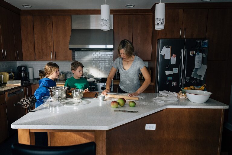 Pullback of mom and two kids in the kitchen where mom is rolling out pie crust