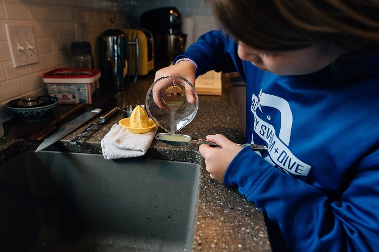 Girl measures lemon juice into a tablespoon for apple pie day