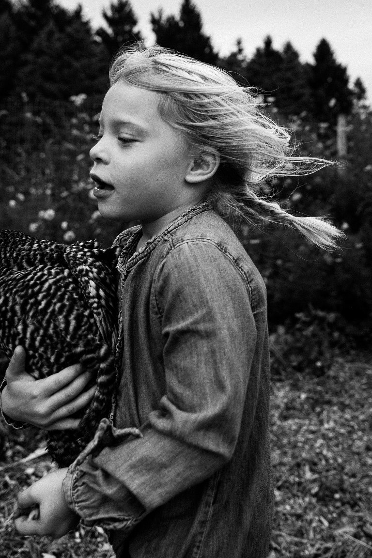 girl running with hair blown back while holding a chicken