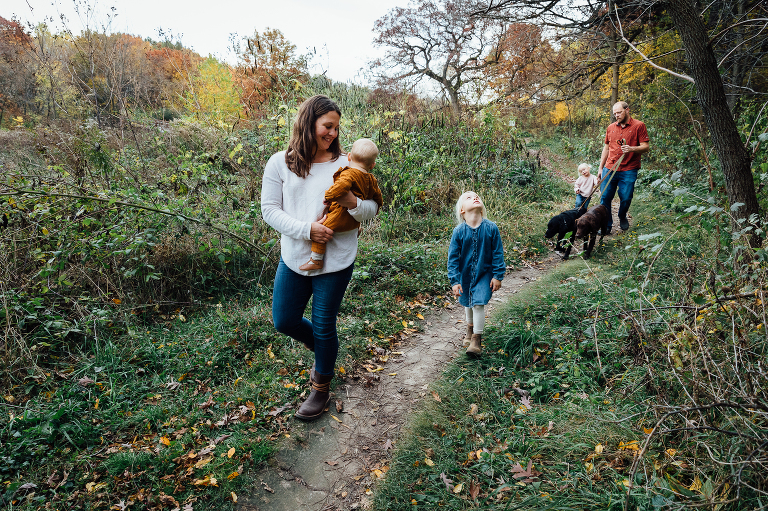 family of five walk on a dirt path in an autumn forest
