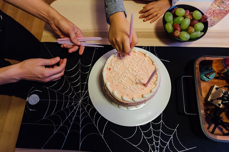 mom and daughter put purple candles on a pink birthday cake