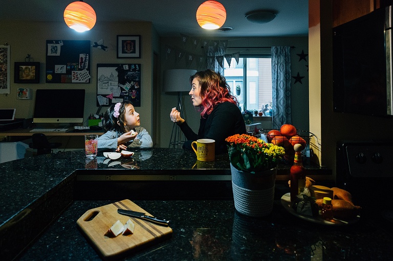 mom and daughter sit at kitchen bar, talk and eat apples