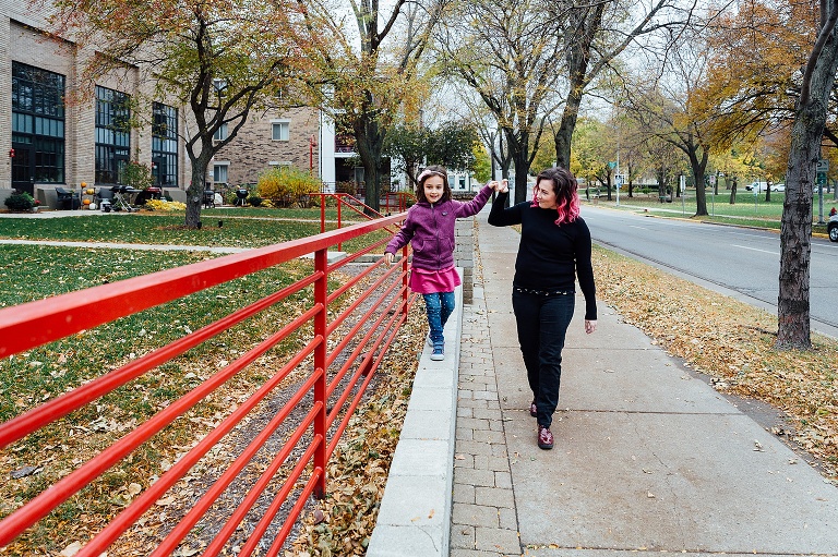 daughter balances on a brick paver while mom holds her hand for extra balance 