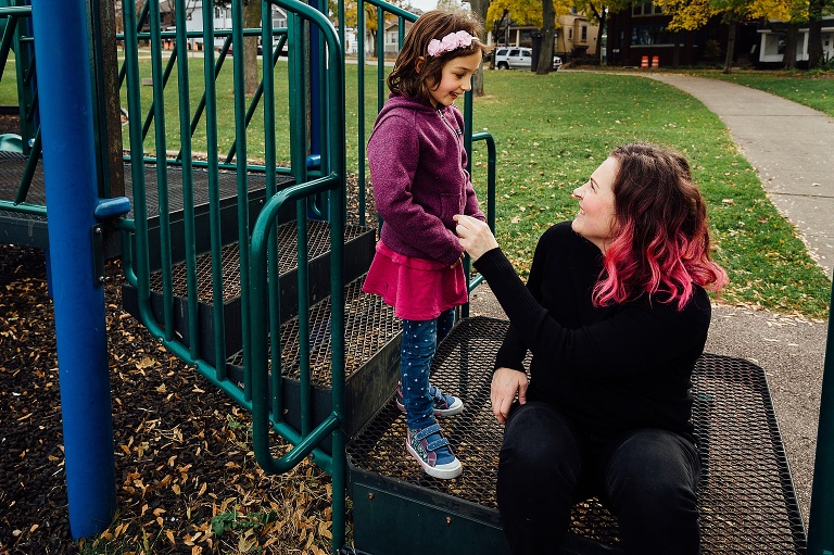 mom and girl smile on playground equipment 